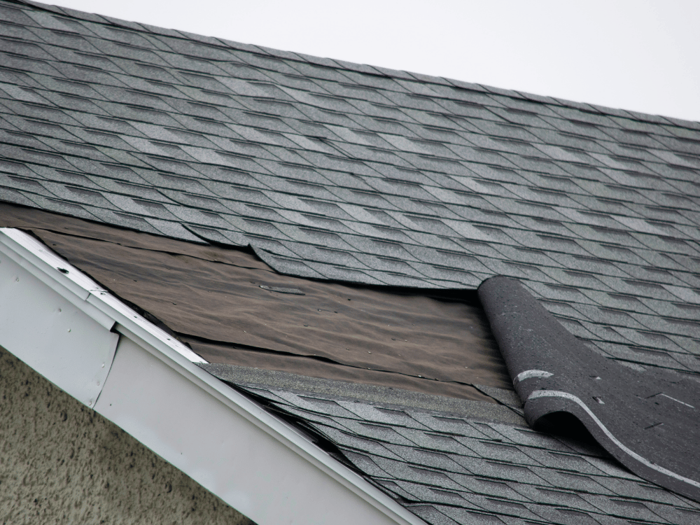 TwinAnchors_FeaturedImagesTwinAnchors_FeaturedImages_StormDamage Storm-damaged asphalt shingles exposing the roof deck repaired by Twin Anchors Roofing
